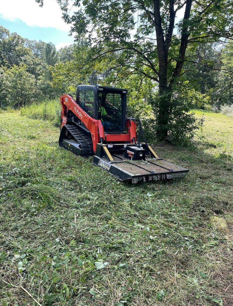 Skid steer brush hogging a field